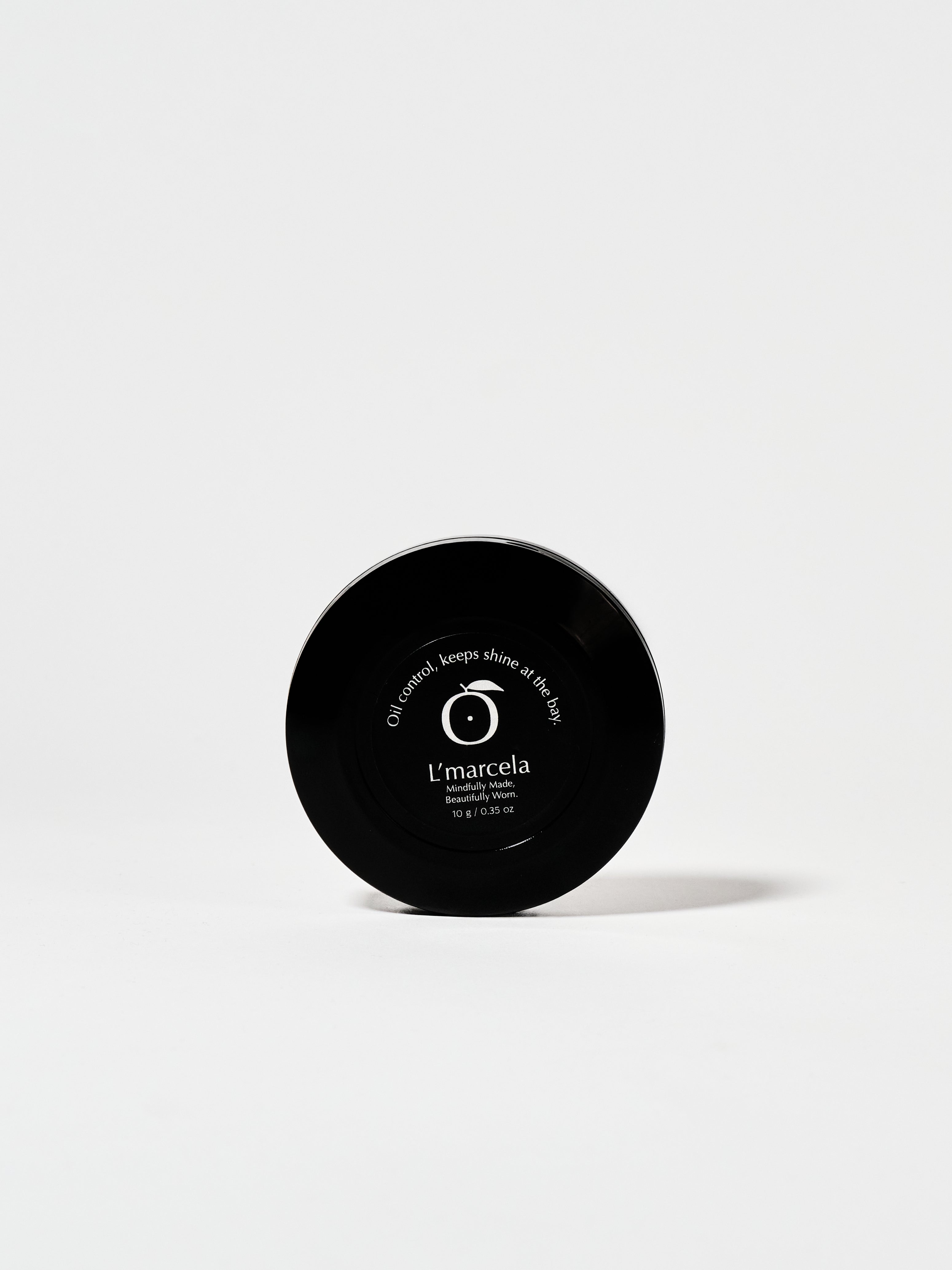 Bottom view of L’Marcela Setting Powder compact with product label, emphasizing its long-lasting, shine-controlling formula.